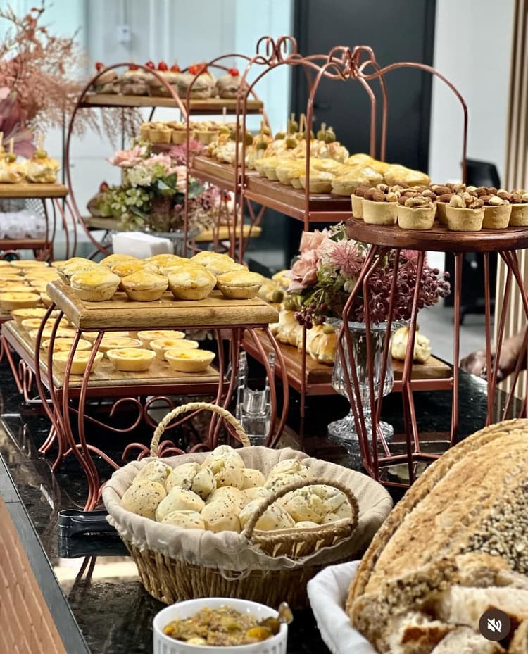 Mesa de Coffee Break empresarial com pães doces frutas e queijos