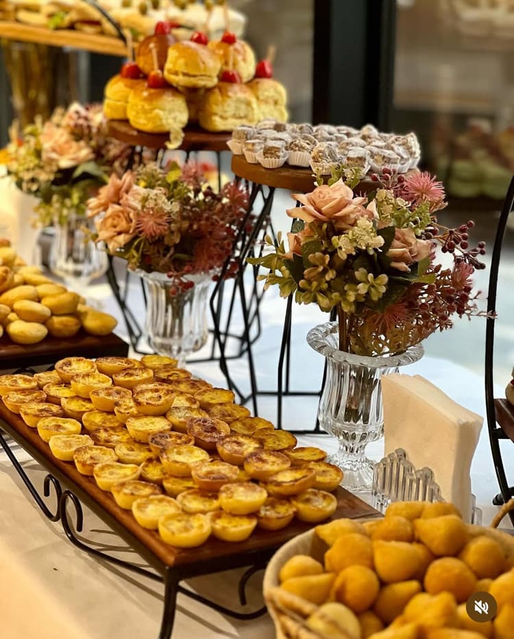 Mesa de Coffee Break empresarial com pães doces frutas e queijos