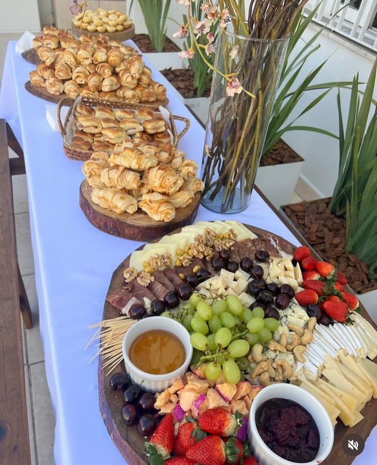 Mesa de Coffee Break empresarial com pães doces frutas e queijos